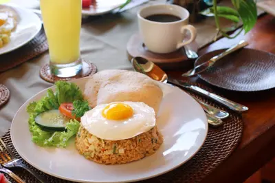 a plate of food with an egg and bread on a table at Sudha Villa Bali B in Seminyak