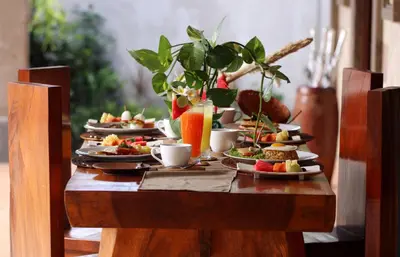 a wooden table with plates of food on it at Sudha Villa Bali B in Seminyak