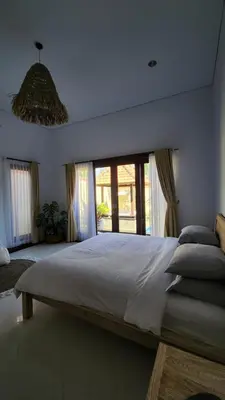 a bedroom with a large bed with a large window at Villa Margherita in Seminyak