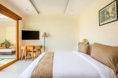 a bedroom with a bed and a table and a television at Taman Sari Pengubengan Villa in Kerobokan