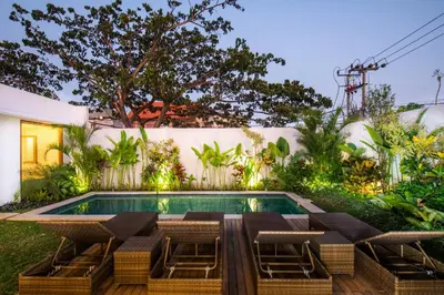 a swimming pool with a table and chairs next to a house at Taman Sari Pengubengan Villa in Kerobokan