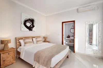 a white bedroom with a large bed and a mirror at Villa Maleena in Seminyak