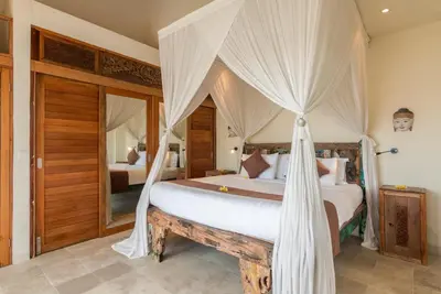 a bedroom with a large bed with mosquito nets at Villa Beji in Seminyak