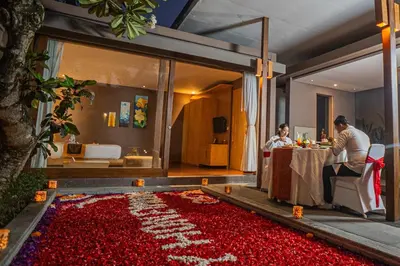 two people sitting at a table in a room filled with red flowers at Asa Bali Luxury Villas & Spa in Seminyak