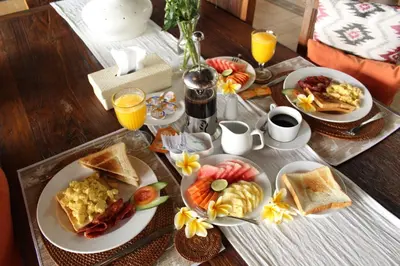 a table topped with plates of breakfast foods and orange juice at Casa Jimbaran Villa in Jimbaran