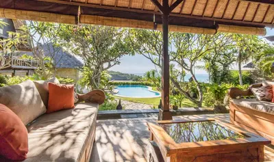a patio with a couch and a table and a pool at Casa Jimbaran Villa in Jimbaran