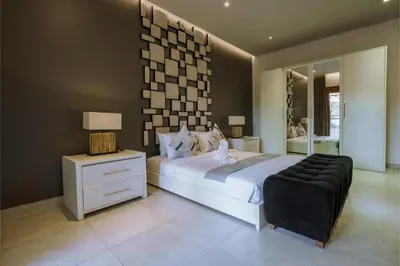 a bedroom with a large bed and a black chair at Villa Orange 3BR Seminyak by Exotic Bali Properties in Seminyak