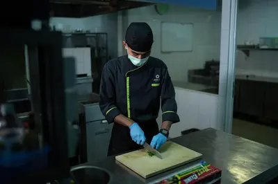 a man in a kitchen cutting a cutting board with a knife at Grand Livio Kuta Hotel in Legian