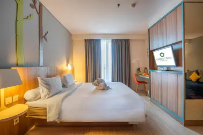 a hotel room with a large bed and a desk at Grand Livio Kuta Hotel in Legian