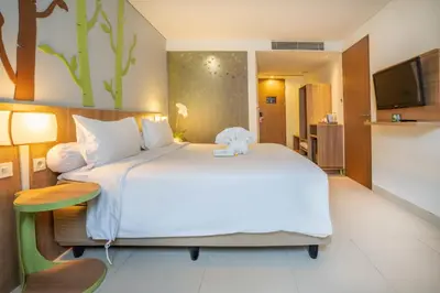 a bedroom with a large bed with a teddy bear on it at Grand Livio Kuta Hotel in Legian
