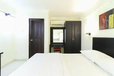 a bedroom with a white bed and a black door at Permisol Homestay 88 in Denpasar