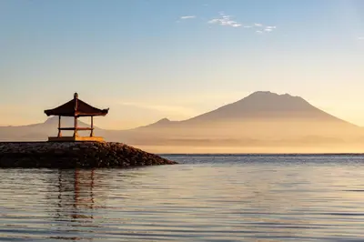 a small island in the water with a mountain in the background at Four Star by Trans Hotel in Sanur