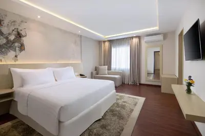 a bedroom with a large white bed and a couch at Four Star by Trans Hotel in Sanur