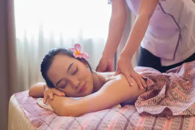 a woman laying on a bed getting a massage at Four Star by Trans Hotel in Sanur