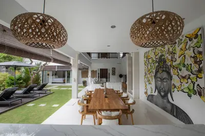 a dining room with a table and chairs and a painting at Mahasari Villa in Seminyak
