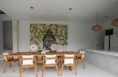 a dining room with a table with chairs and a painting at Mahasari Villa in Seminyak