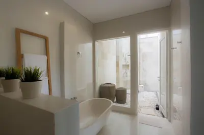 a white bathroom with a tub and a glass shower at Mahasari Villa in Seminyak
