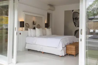a bedroom with a white bed and a portrait of a woman at Mahasari Villa in Seminyak