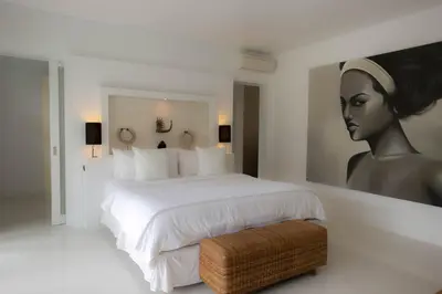 a bedroom with a bed with a painting of a woman at Mahasari Villa in Seminyak