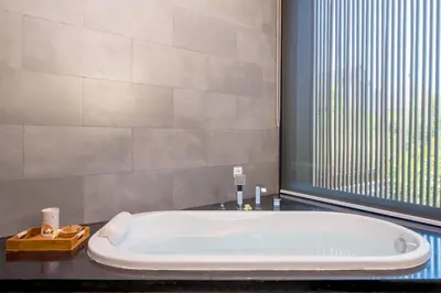 a bath tub in a bathroom with a large window at Villa DeDayuh Seminyak in Seminyak