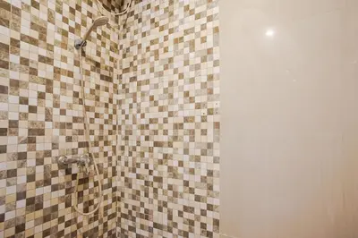 a bathroom with a shower with a tiled wall at Mahesa Suites Seminyak in Seminyak
