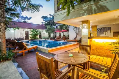 a patio with a table and chairs and a swimming pool at KELAN-TEL BALI in Jimbaran