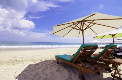two chairs and an umbrella on a beach at KELAN-TEL BALI in Jimbaran