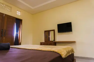 a bedroom with a bed and a flat screen tv on the wall at Cakra House in Denpasar