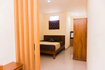 a bedroom with a bed and a wooden door at Cakra House in Denpasar