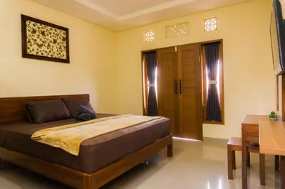 a bedroom with a bed and a table and a door at Cakra House in Denpasar