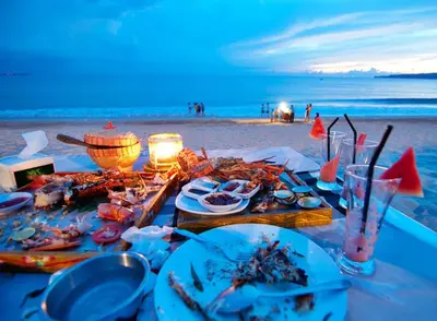 a table with plates of food on the beach at Kedonganan Beach Villas in Jimbaran