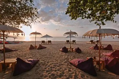 a beach with tables and umbrellas on the sand at Kedonganan Beach Villas in Jimbaran