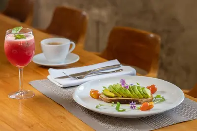 a table with a plate with a sandwich and a drink at Huge 11 BR Villa, Sleeps 41, Prime Area, Near Beach in Canggu