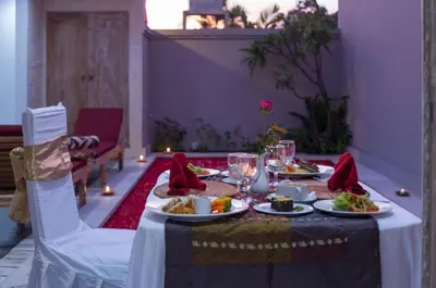 a table with plates of food and glasses on it at The Awandari Villas Seminyak in Seminyak
