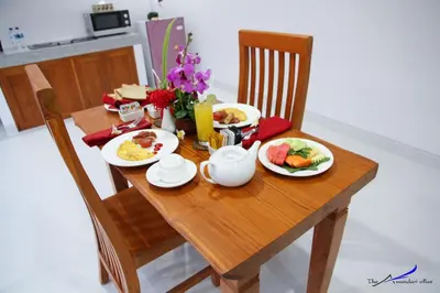 a wooden table with plates of breakfast food on it at The Awandari Villas Seminyak in Seminyak