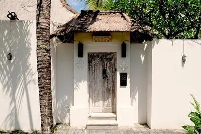 a white house with a door and a palm tree at Villa de Malicott in Seminyak
