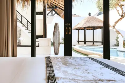 a bedroom with a bed and a view of a pool at Villa de Malicott in Seminyak