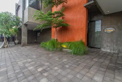 a tree in front of a building with grass at D Home Seminyak in Seminyak