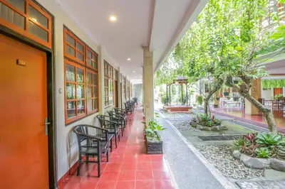 a corridor of a building with chairs and trees at Catur Adi Putra in Denpasar