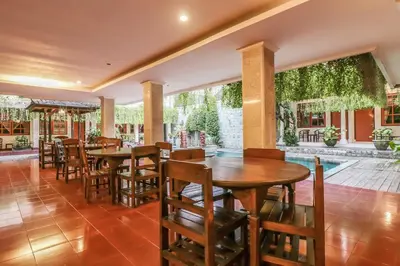 a restaurant with tables and chairs and a pool at Catur Adi Putra in Denpasar