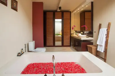 a bathroom with a sink with red flowers in it at Imani Villas in Canggu
