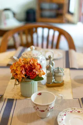 a table with a vase of flowers and a cup at Villa Retro 88 in Seminyak