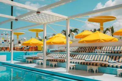 a pool with chairs and umbrellas next to a swimming pool at Villa Retro 88 in Seminyak