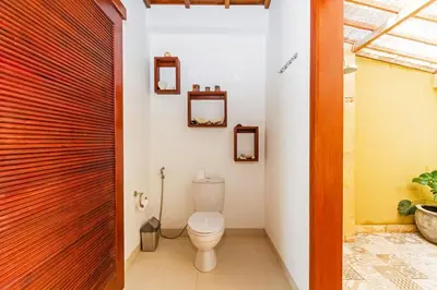 a bathroom with a toilet and a wooden door at Awesome 1BR Villa in the heart of Seminyak in Seminyak