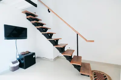 a living room with stairs with a tv and chairs at D'Tamblingan Guest House at Taman Griya Jimbaran RedPartner - Minimum Stay 30 Nights in Jimbaran