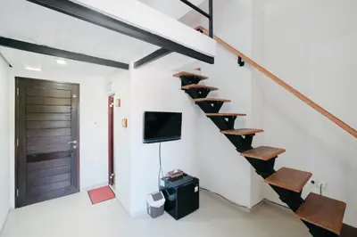 a room with a staircase with a tv and a door at D'Tamblingan Guest House at Taman Griya Jimbaran RedPartner - Minimum Stay 30 Nights in Jimbaran