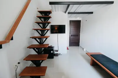 a staircase in a house with wooden steps and a couch at D'Tamblingan Guest House at Taman Griya Jimbaran RedPartner - Minimum Stay 30 Nights in Jimbaran