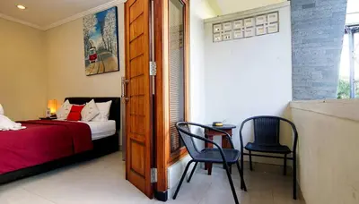 a bedroom with a bed and a table and a chair at Kuta Paradise 777 in Legian