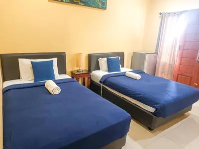 two beds in a room with blue and white sheets at Kuta Paradise 777 in Legian