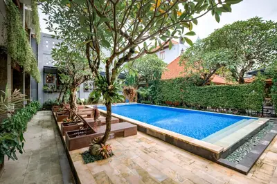 a swimming pool with a tree and benches around it at D Sarian Seminyak in Seminyak
